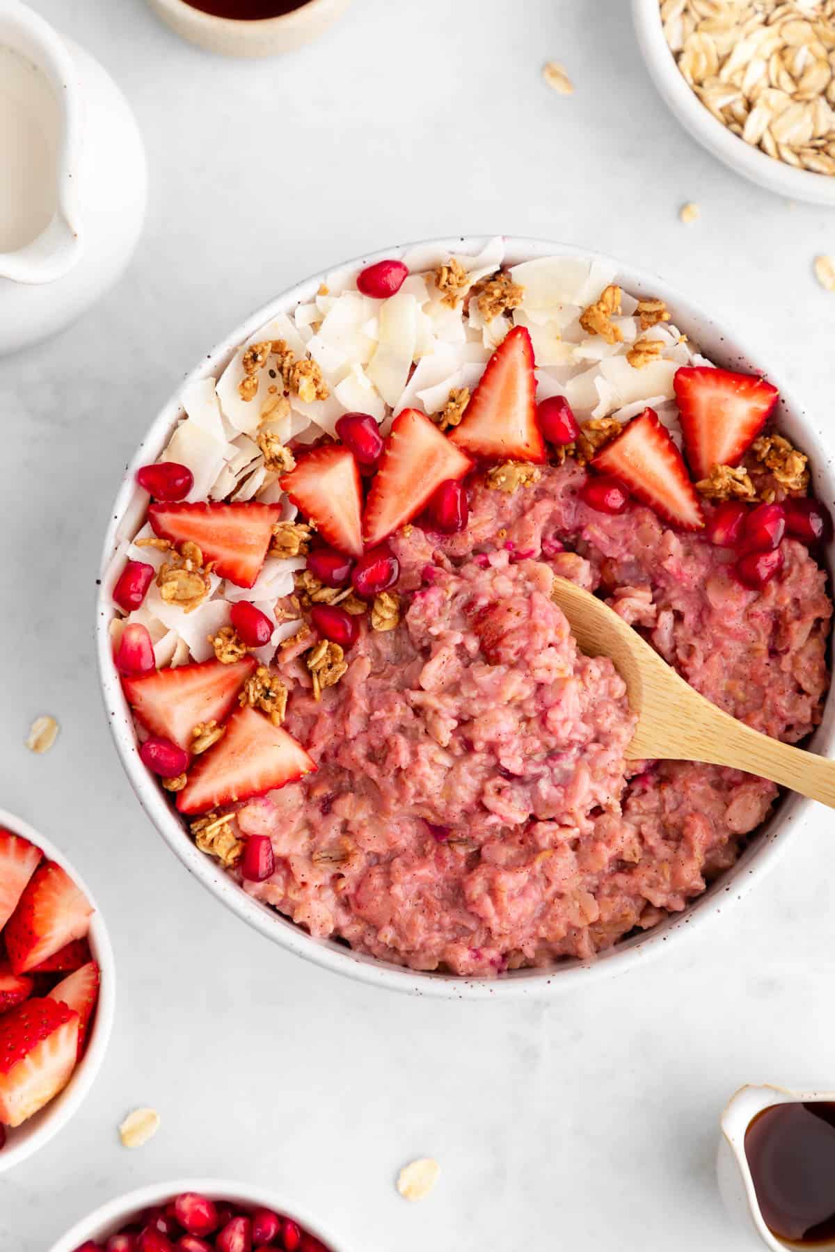 a wooden spoon scooping into a bowl of strawberry oatmeal