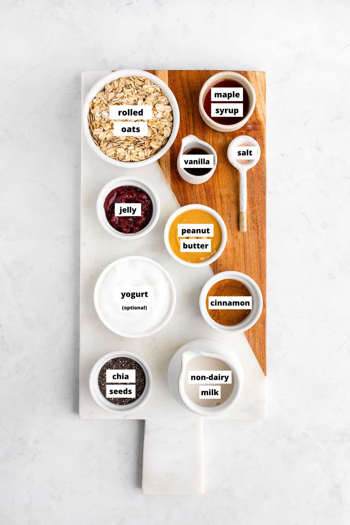 bowls of ingredients for pb and j overnight oats on a wooden serving board