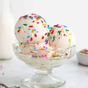 three scoops of coconut milk cake batter ice cream inside a sundae glass