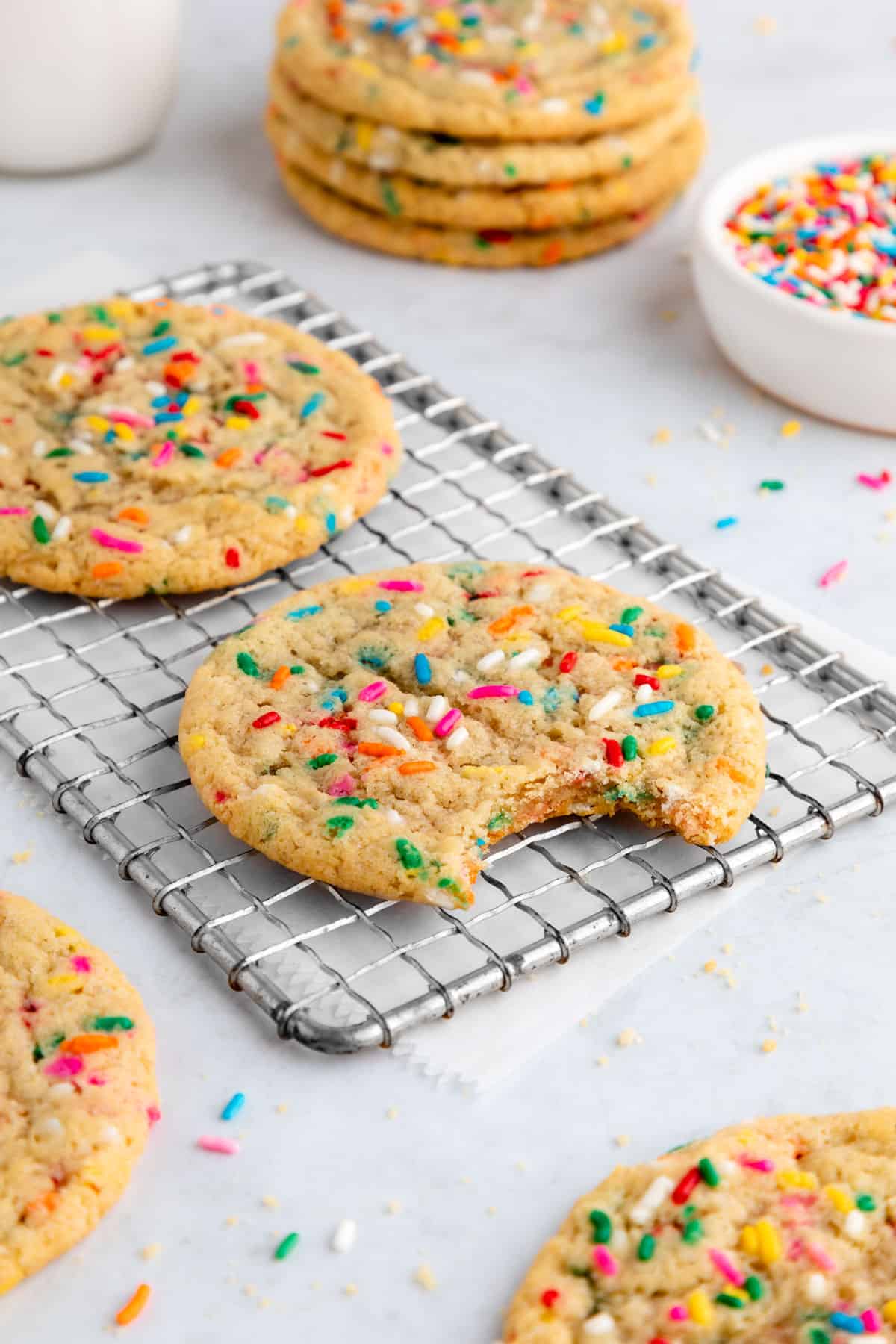 a half bitten vegan funfetti cookie on a wire cooling rack