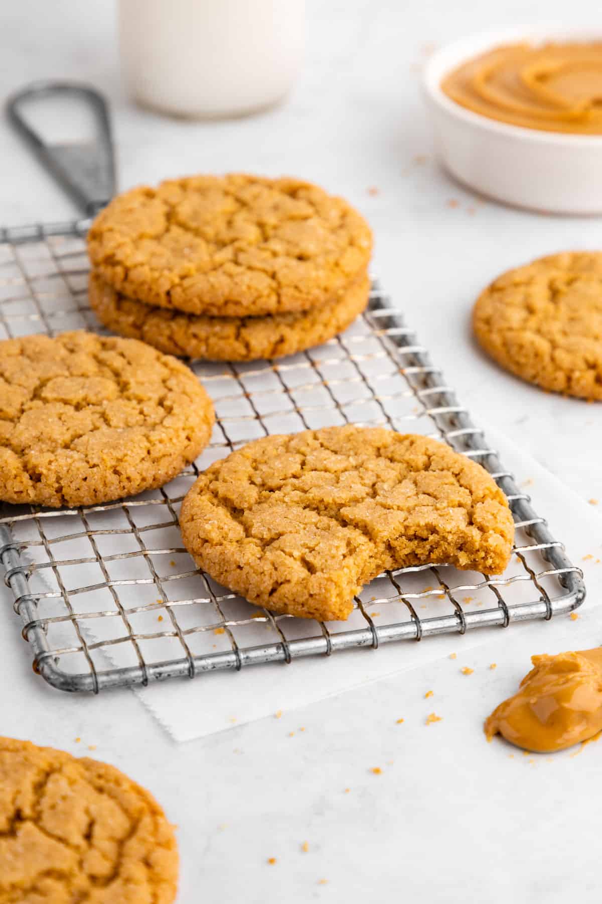 vegan peanut butter cookies on a wire rack with a bite taken out of the middle cookie