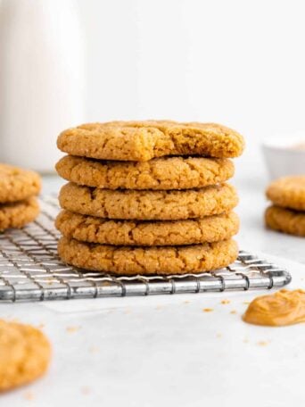 a stack of vegan peanut butter cookies with a bite taken out of the top cookie