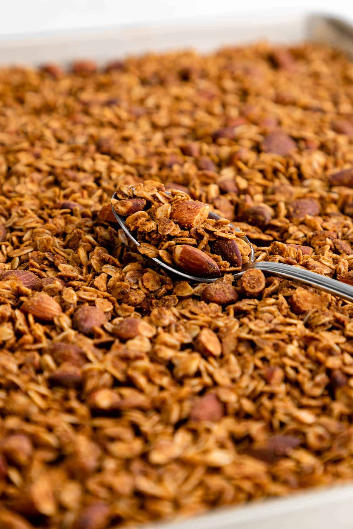 a spoonful of almond butter granola on a baking sheet