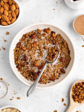 a bowl of homemade almond butter granola with almond milk and a spoon