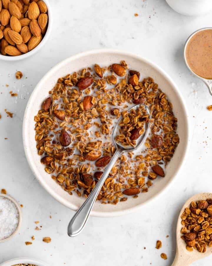 a bowl of homemade almond butter granola with almond milk and a spoon