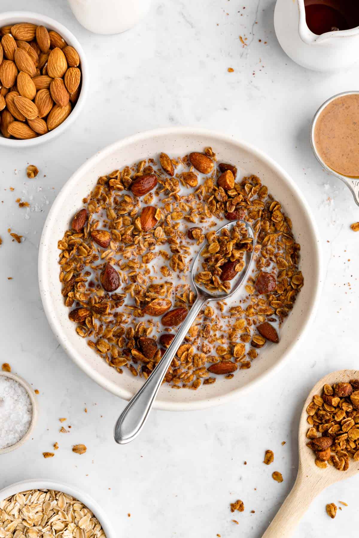 a bowl of homemade almond butter granola with almond milk and a spoon