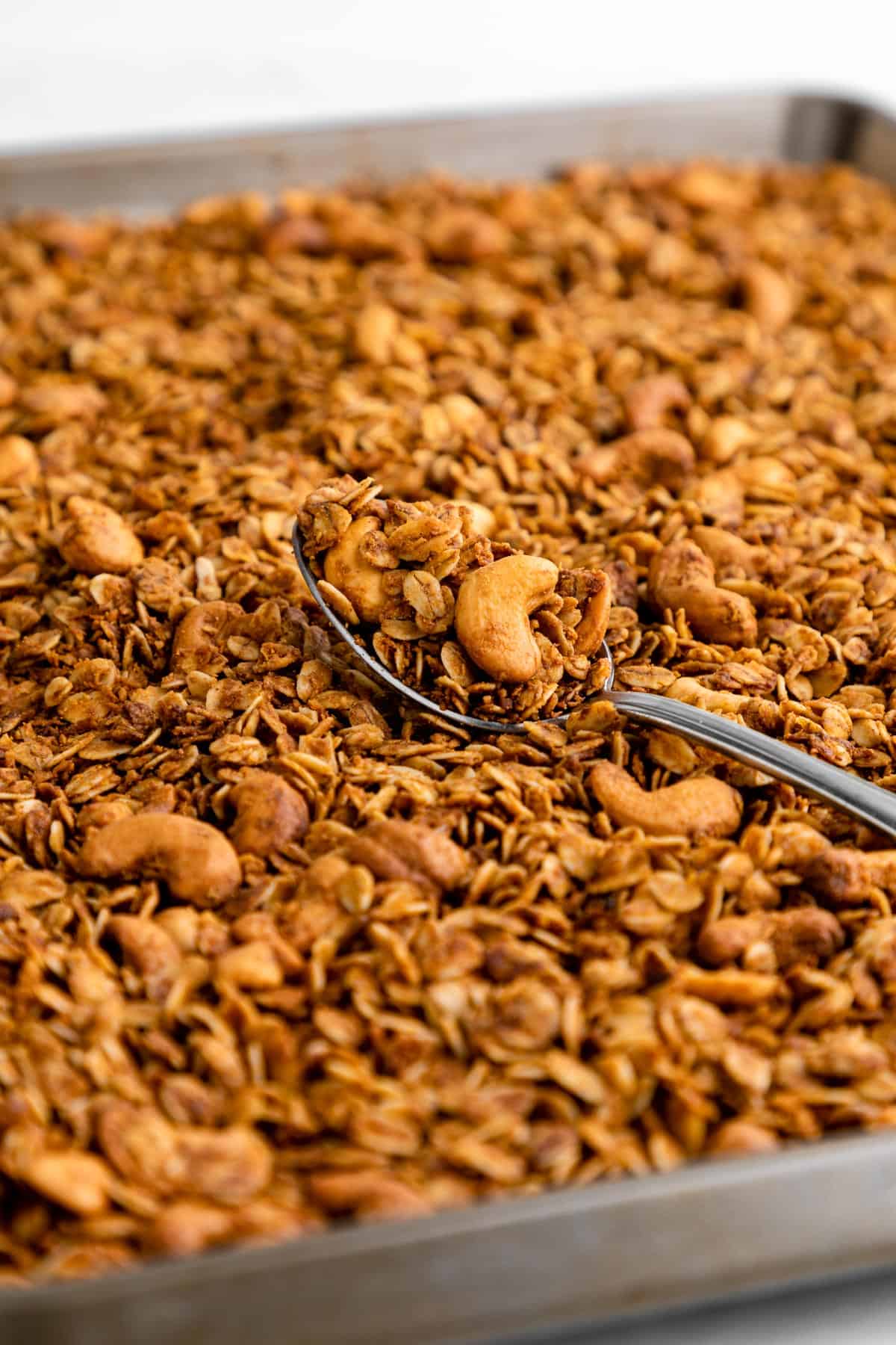 a spoonful of cashew butter granola on a baking sheet
