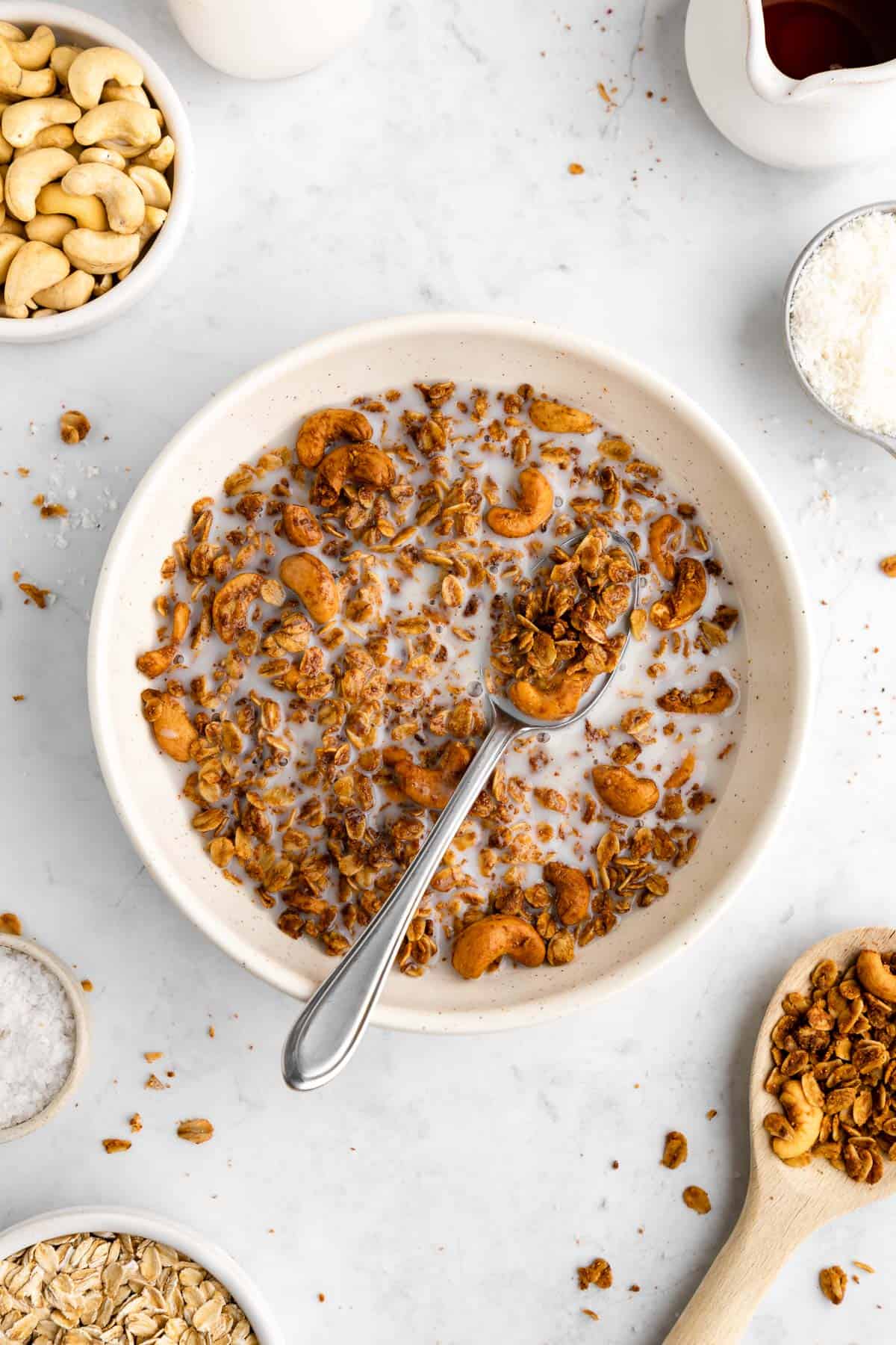 a bowl of cashew butter granola with almond milk and a spoon