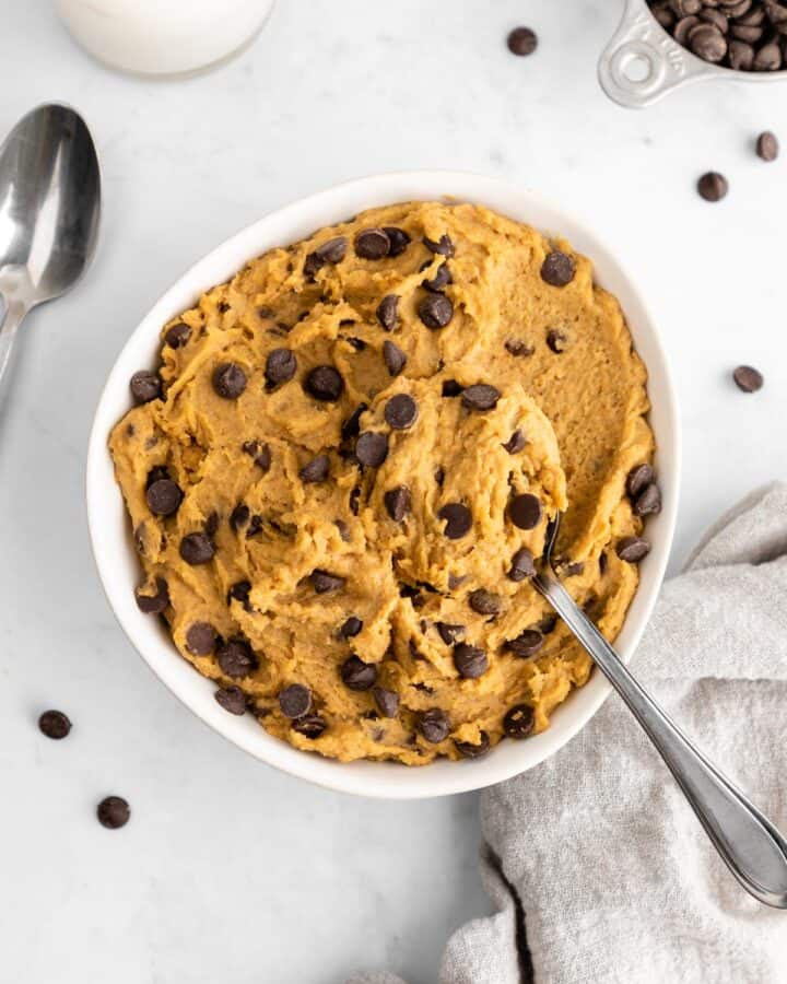 a spoon scooping into a bowl of chickpea cookie dough