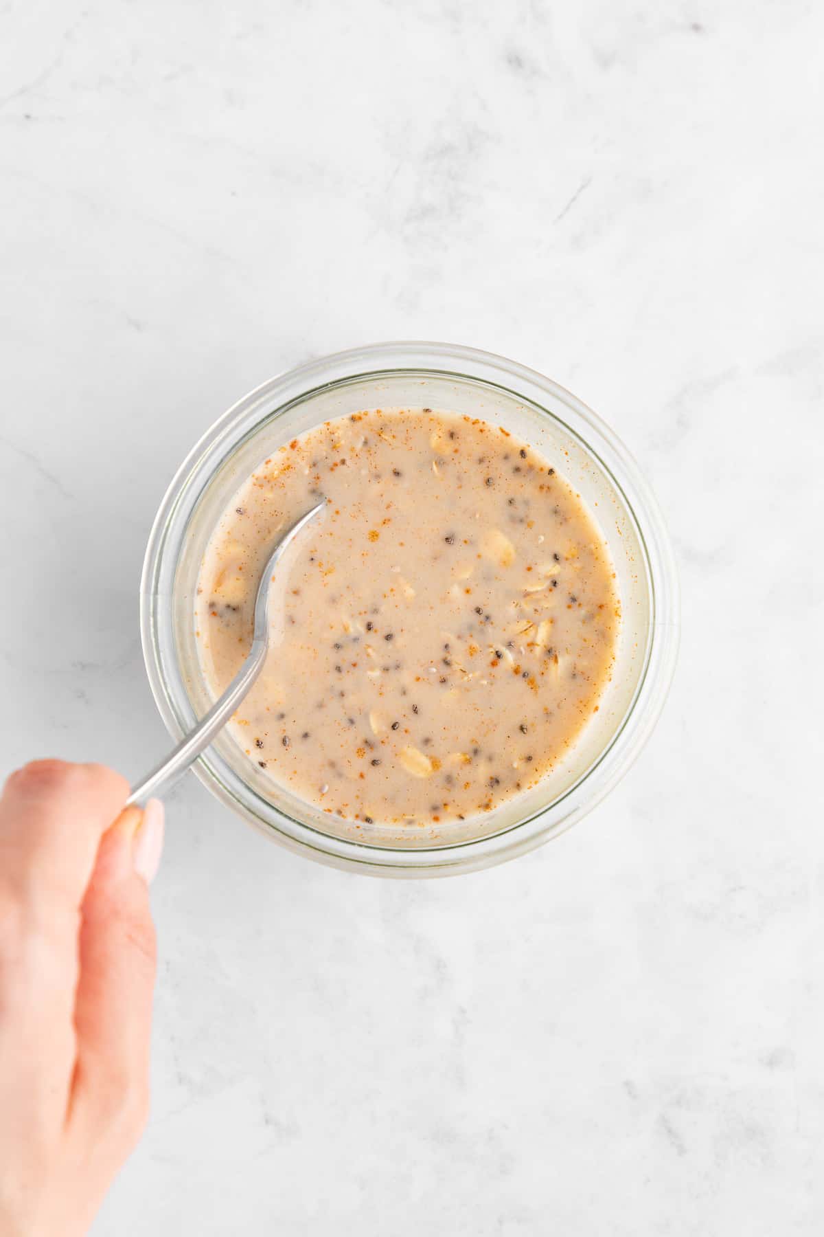 mixing protein overnight oats inside a glass mason jar with a spoon
