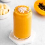 papaya banana smoothie in a glass with a straw