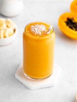 papaya banana smoothie in a glass with a straw