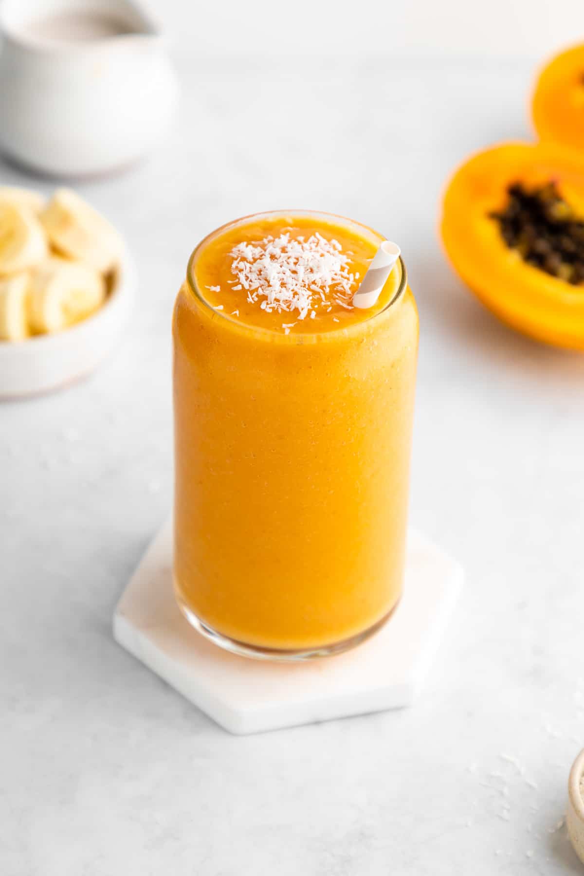 papaya banana smoothie in a glass with a straw