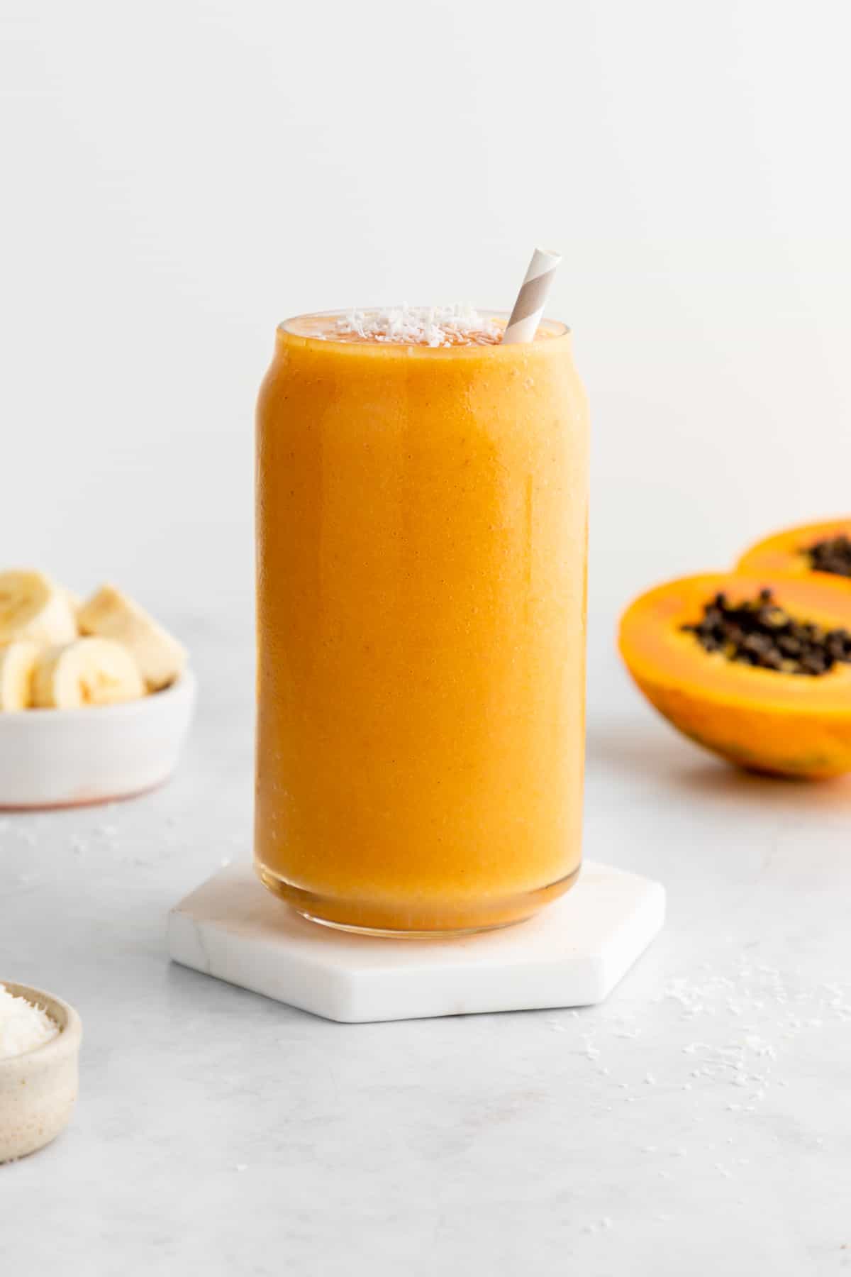 a papaya banana smoothie in a glass with a straw