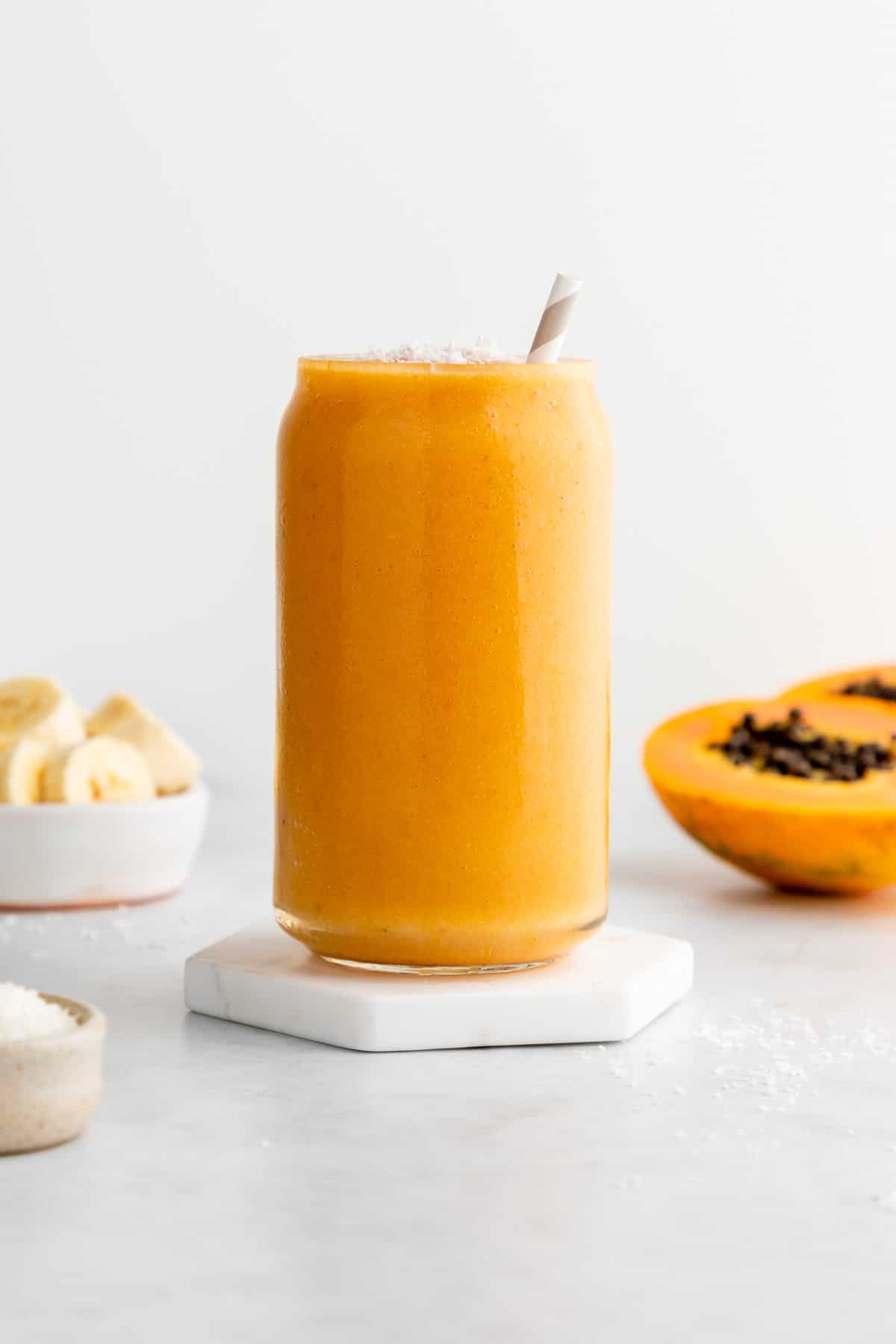 a banana papaya smoothie in a glass with a straw