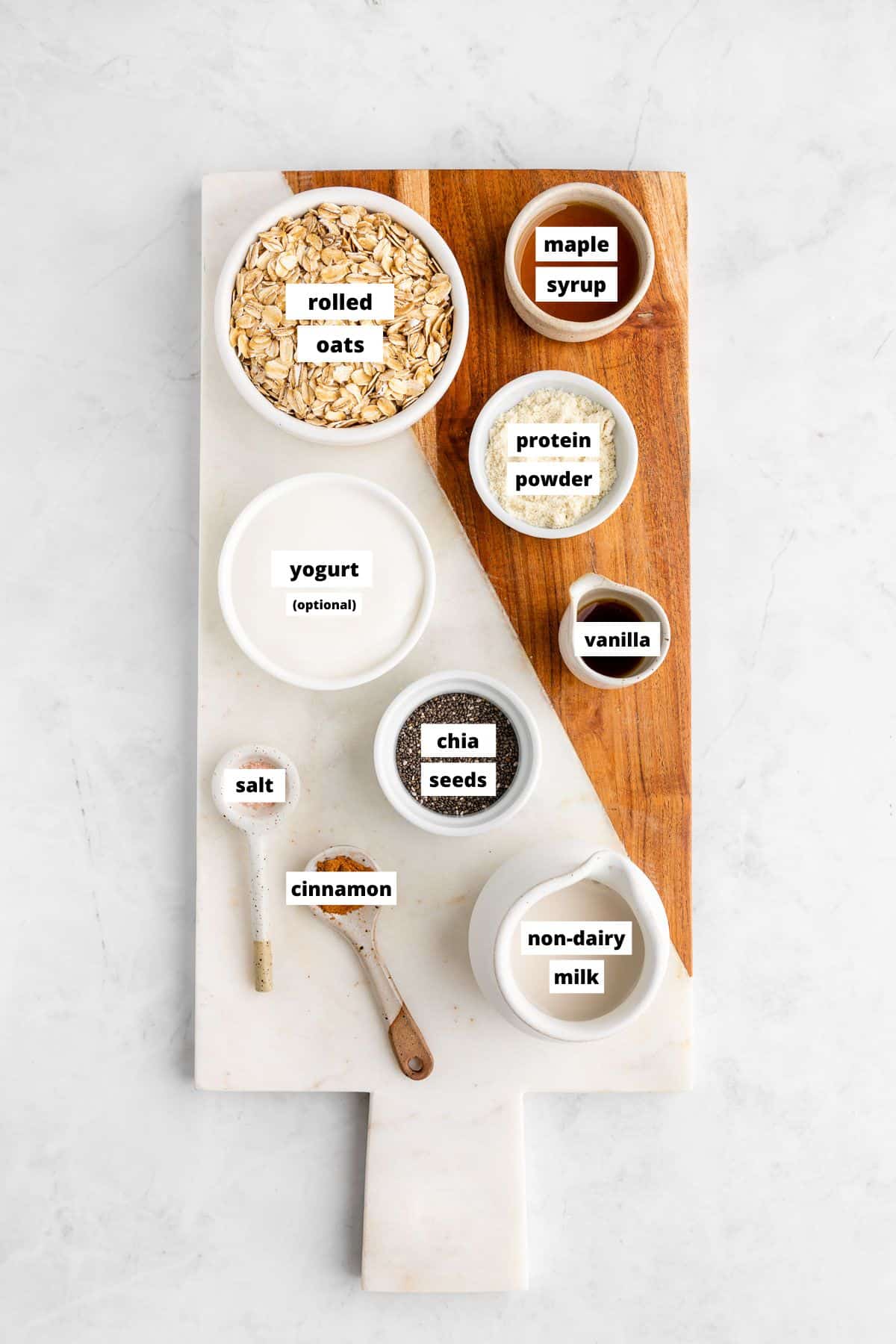 bowls of ingredients for protein overnight oats on a marble serving board