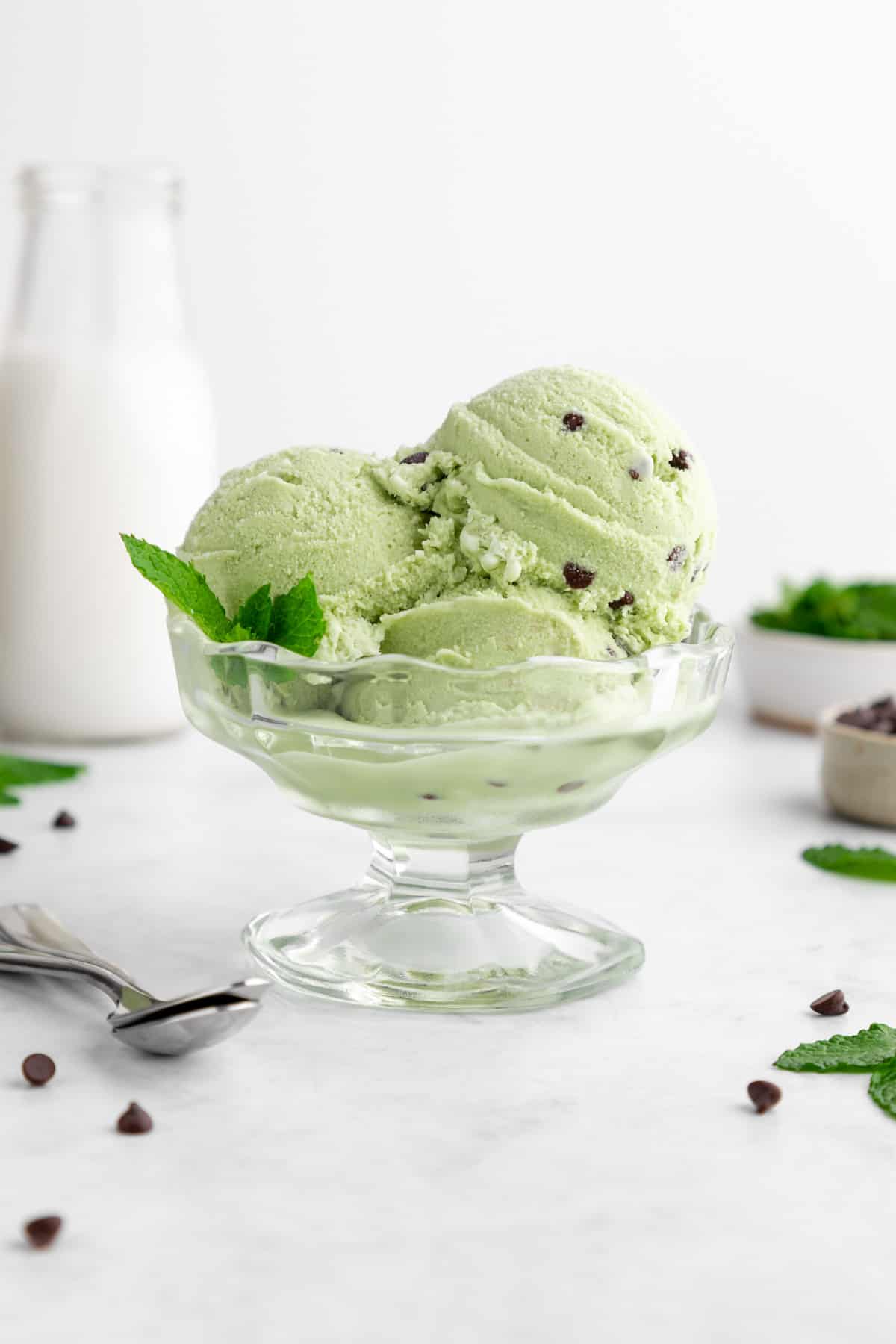 three scoops of vegan mint chocolate chip ice cream in a sundae glass