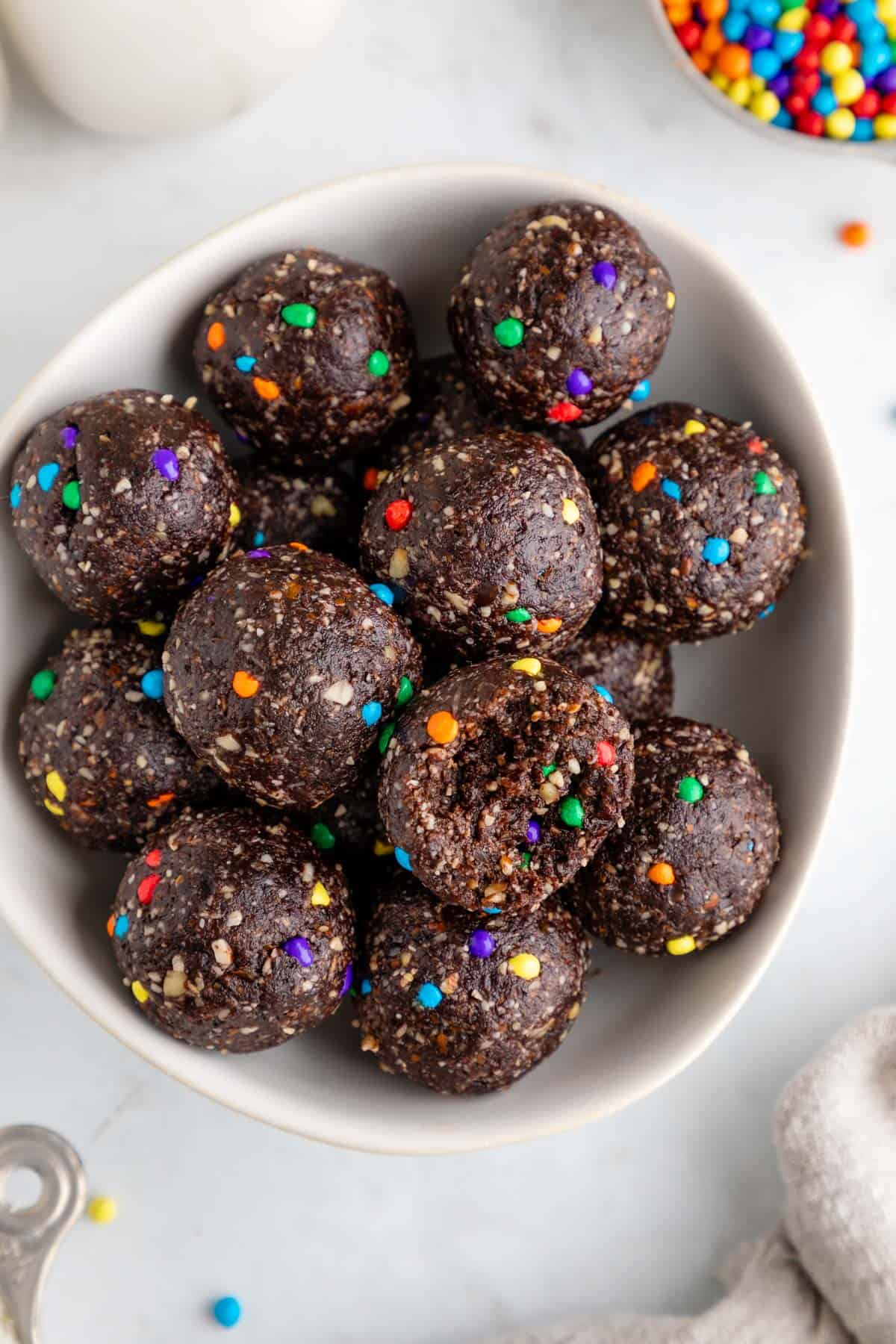 a bowl of healthy cosmic brownie balls with a bite taken out of the center one