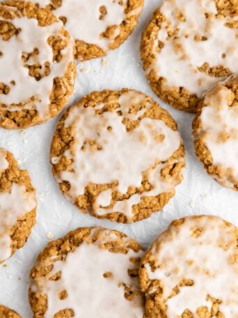 a pile of vegan iced oatmeal cookies with vanilla frosting