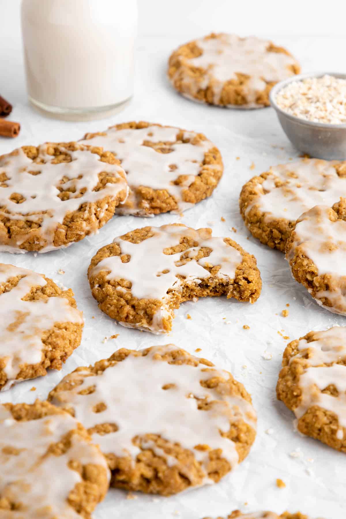 a pile of vegan iced oatmeal cookies with a bite taken out of the center one