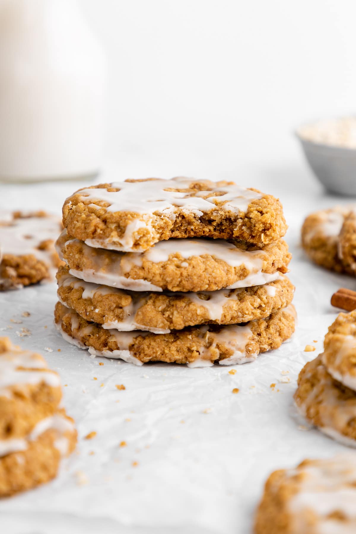 a stack of four vegan iced oatmeal cookies with a bite taken out of the top cookie