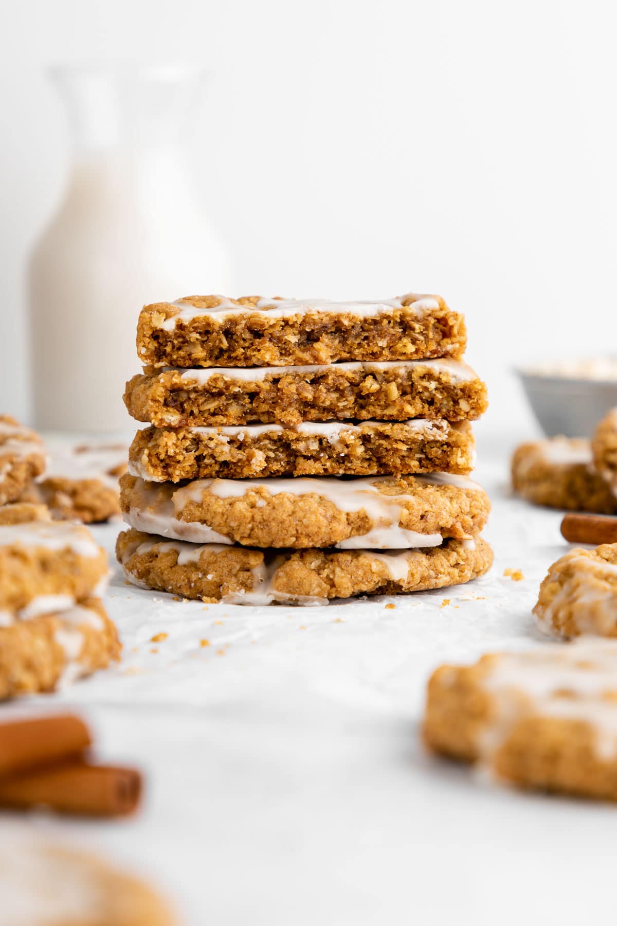 a stack of vegan iced oatmeal cookies with a few cut in half showing the soft and chewy texture