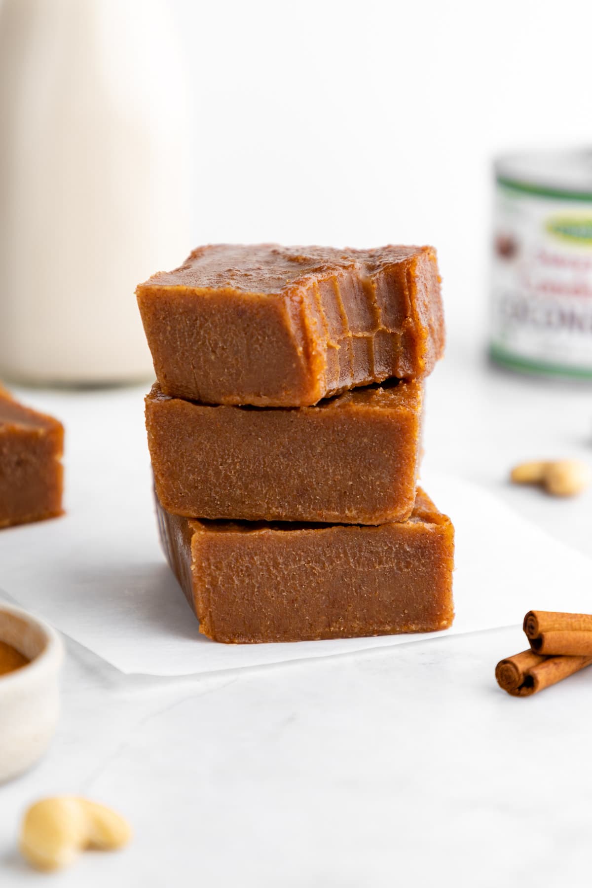 a stack of vegan pumpkin pie fudge squares with a bite taken out of the top one