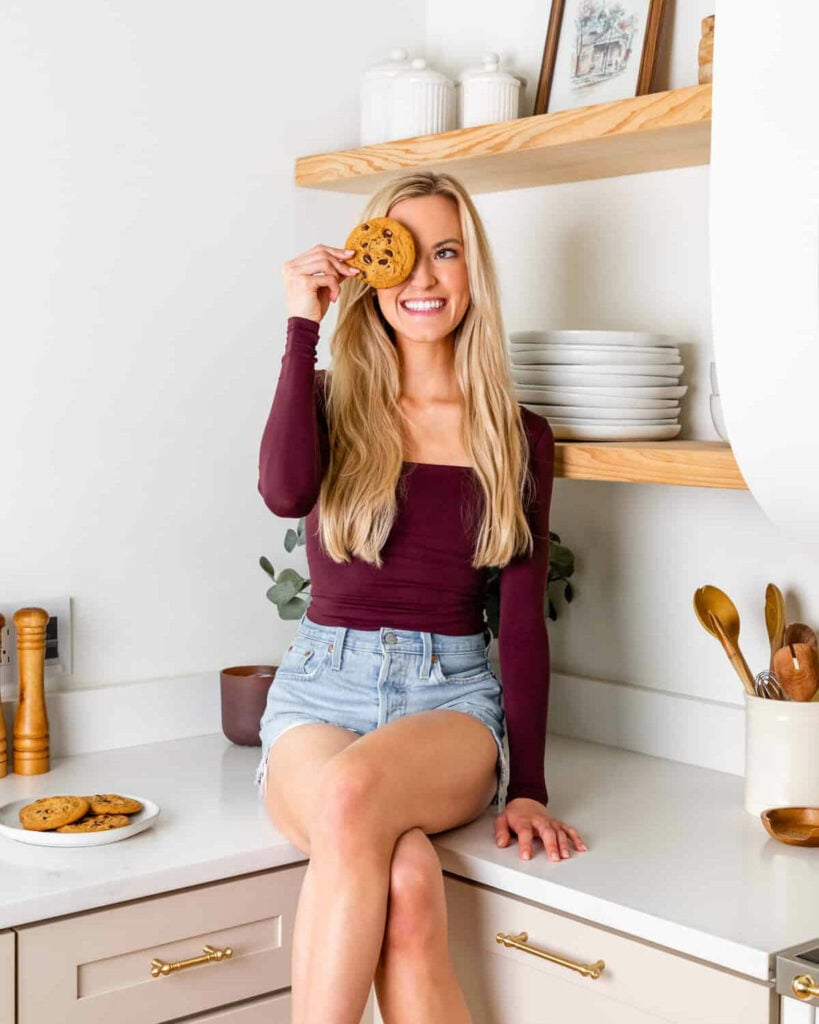 Kaylie sitting on a kitchen counter holding a cookie.