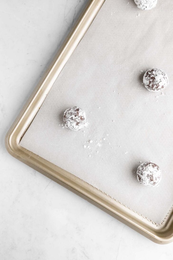 balls of vegan chocolate crinkle cookie dough on a baking sheet