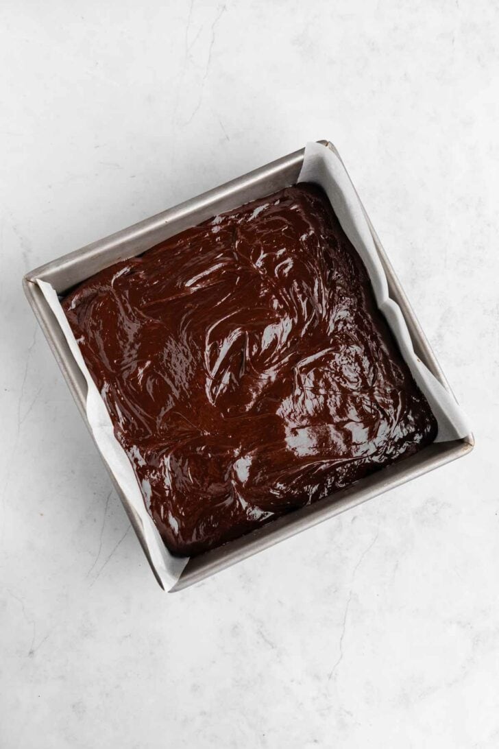 peppermint chocolate ganache spread on top of vegan peppermint brownies inside a square baking dish