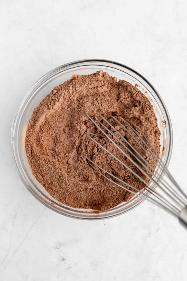 whisking flour, cocoa, and salt inside a glass mixing bowl