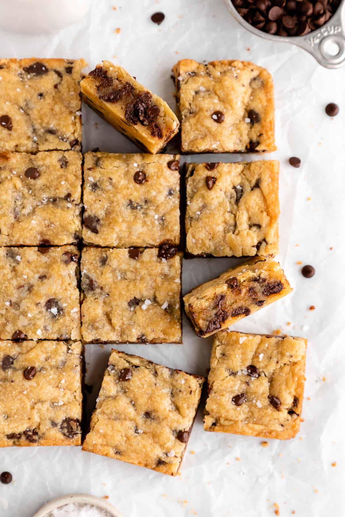 a pile of vegan chocolate chip blondies on white parchment paper