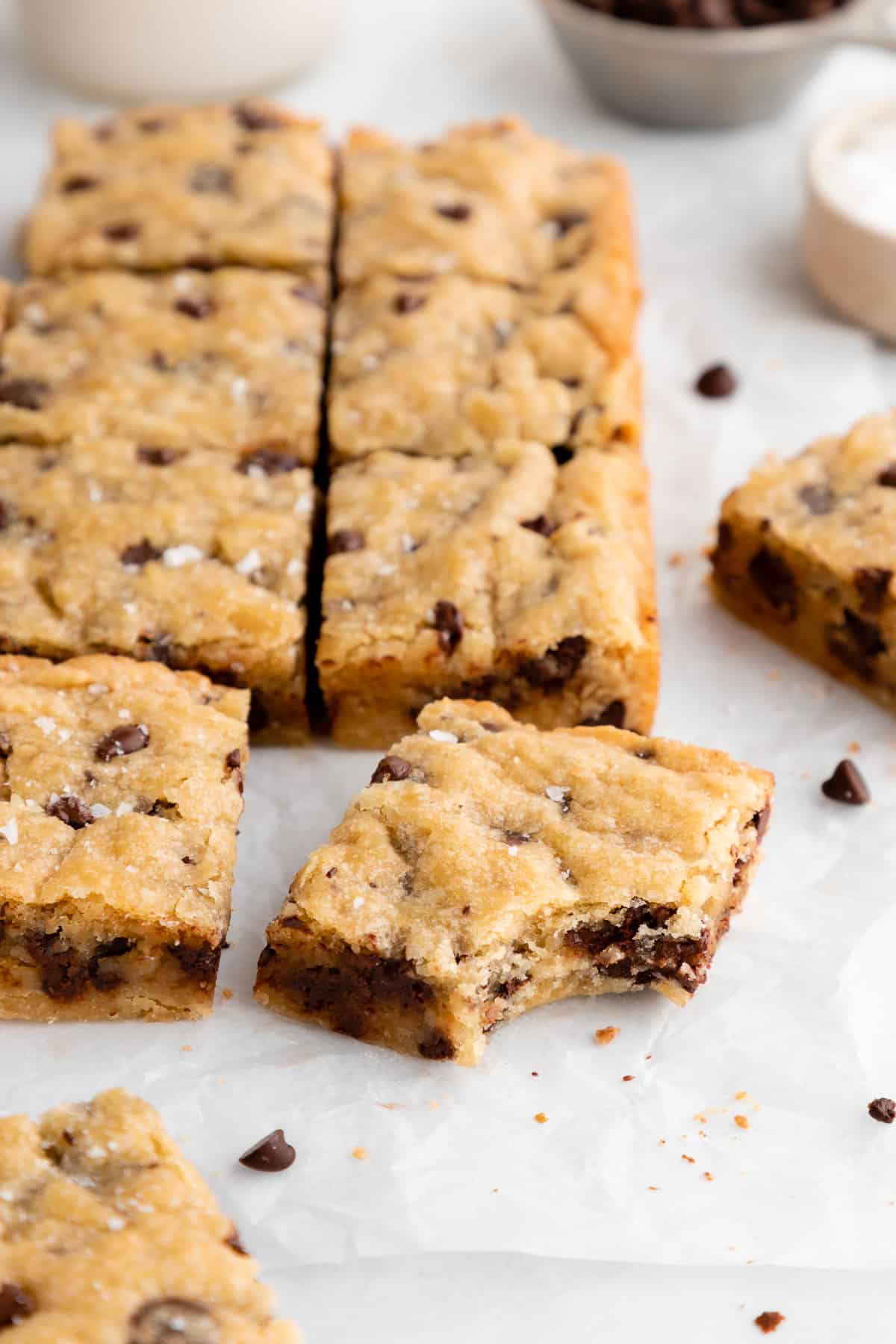 a pile of vegan chocolate chip blondies with a bite taken out of the center one