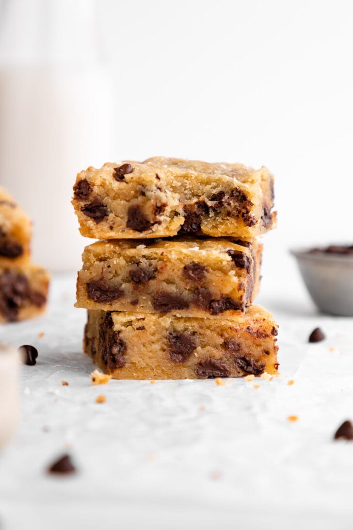 a stack of three vegan chocolate chip blondies with a bite taken out of the top bar