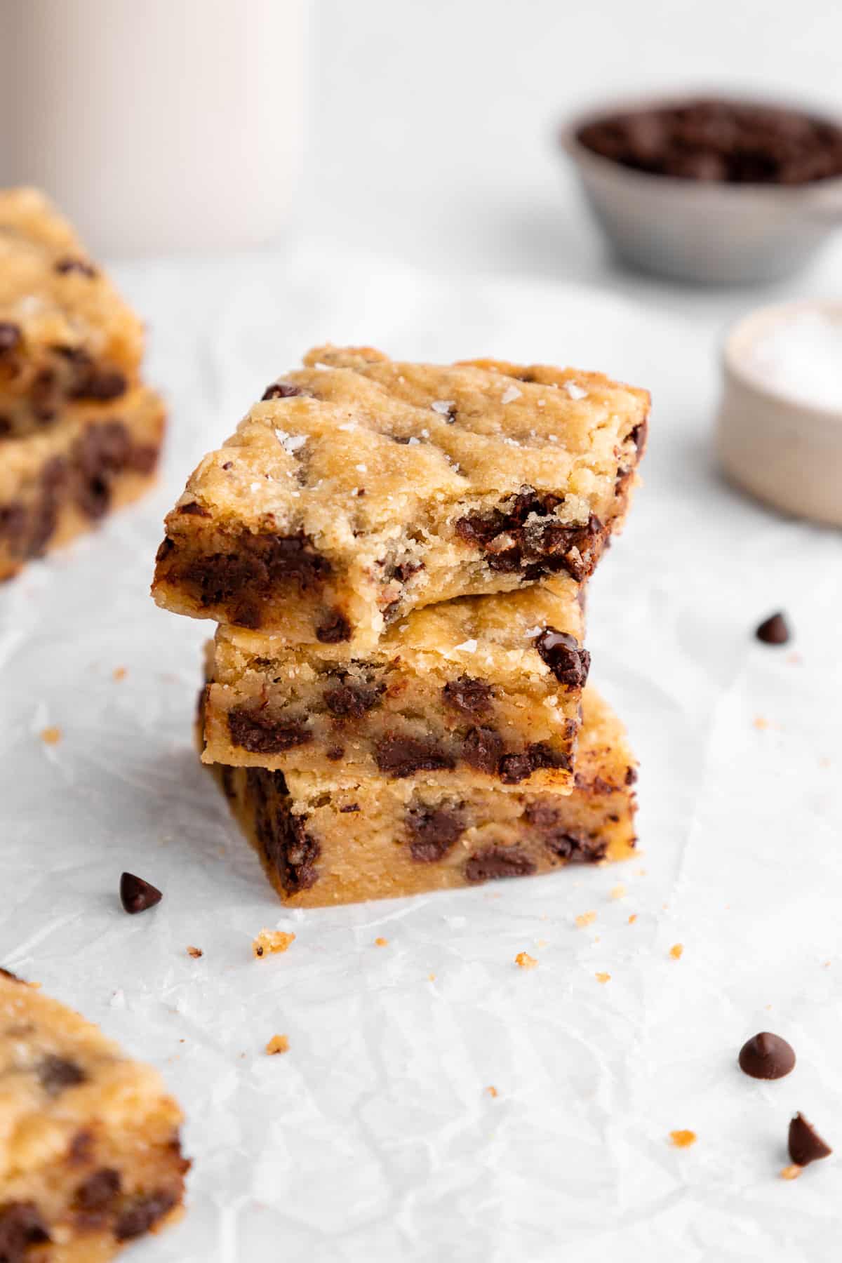 a stack of three vegan chocolate chip blondies with a bite taken out of the top blondie