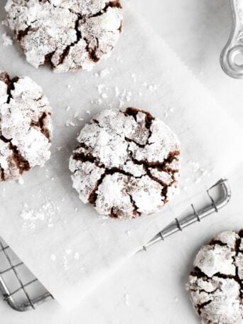 vegan chocolate crinkle cookies with powdered sugar on a wire cooling rack