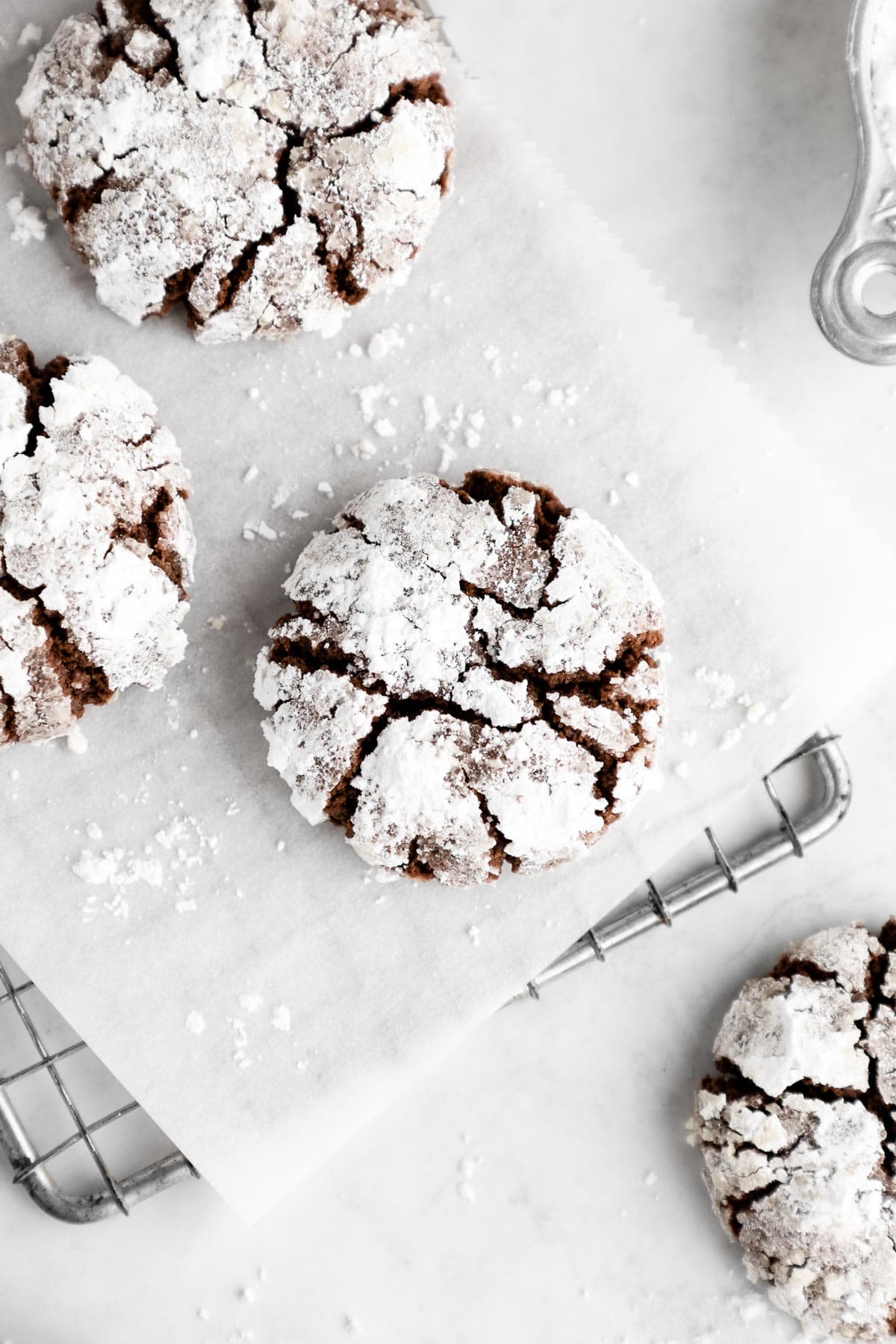 vegan chocolate crinkle cookies with powdered sugar on a wire cooling rack