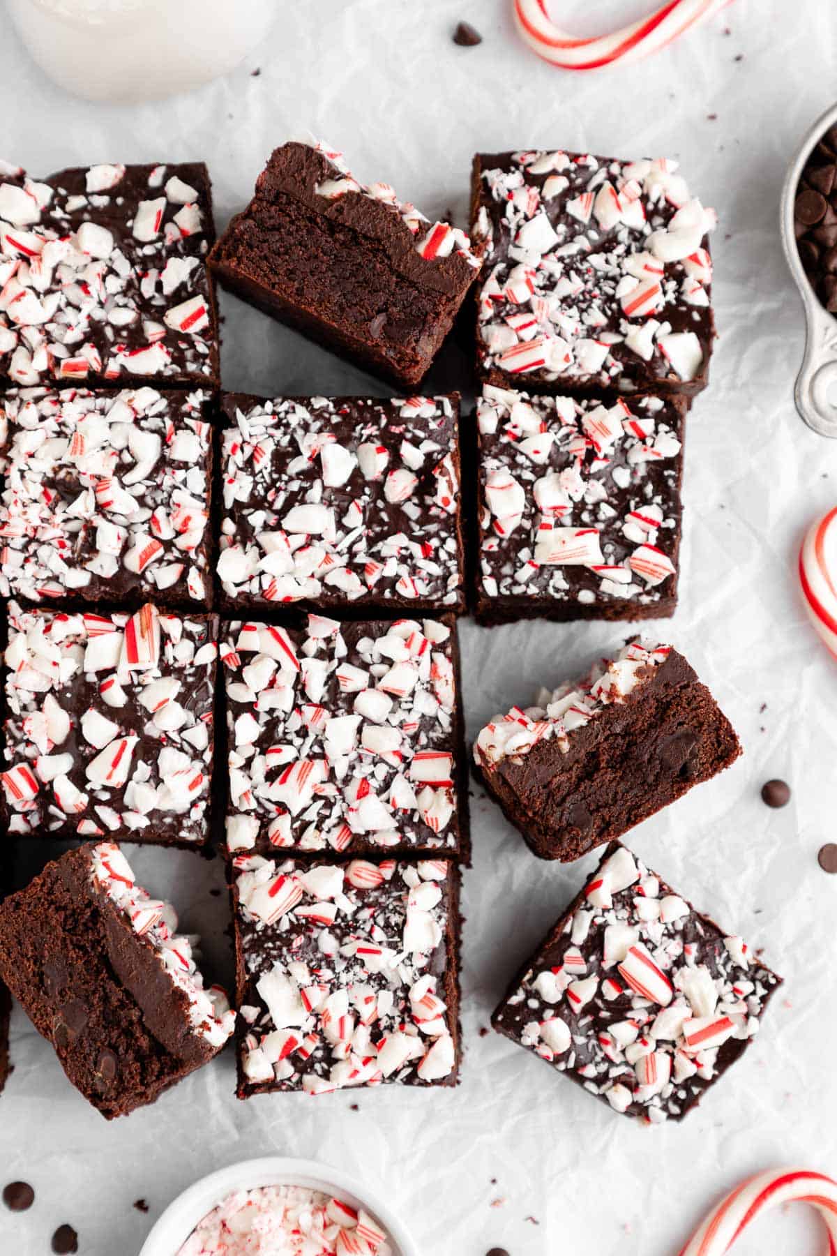 a pile of vegan peppermint brownies topped with chocolate ganache and crushed candy canes