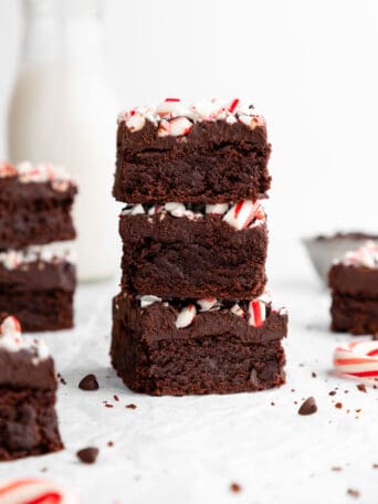 a stack of three vegan peppermint brownies with crushed candy canes and chocolate ganache