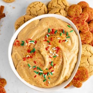 vegan gingerbread cookie dip in a bowl with sprinkles and a plate of holiday cookies