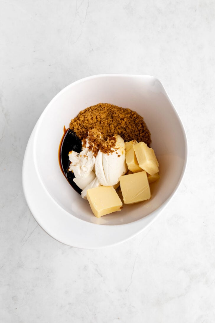 brown sugar, vegan butter, molasses, and vegan cream cheese inside a white mixing bowl