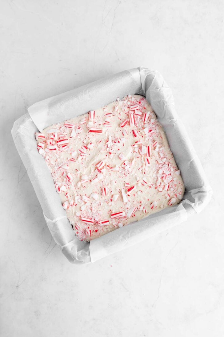 melted vegan white chocolate in a square baking dish with crushed candy canes on top