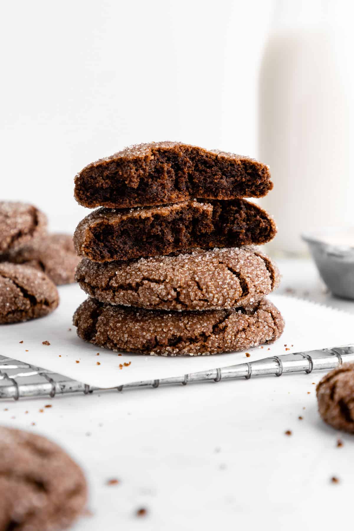 a stack of vegan chocolate sugar cookies on a wire cooling rack with the top two showing the gooey center