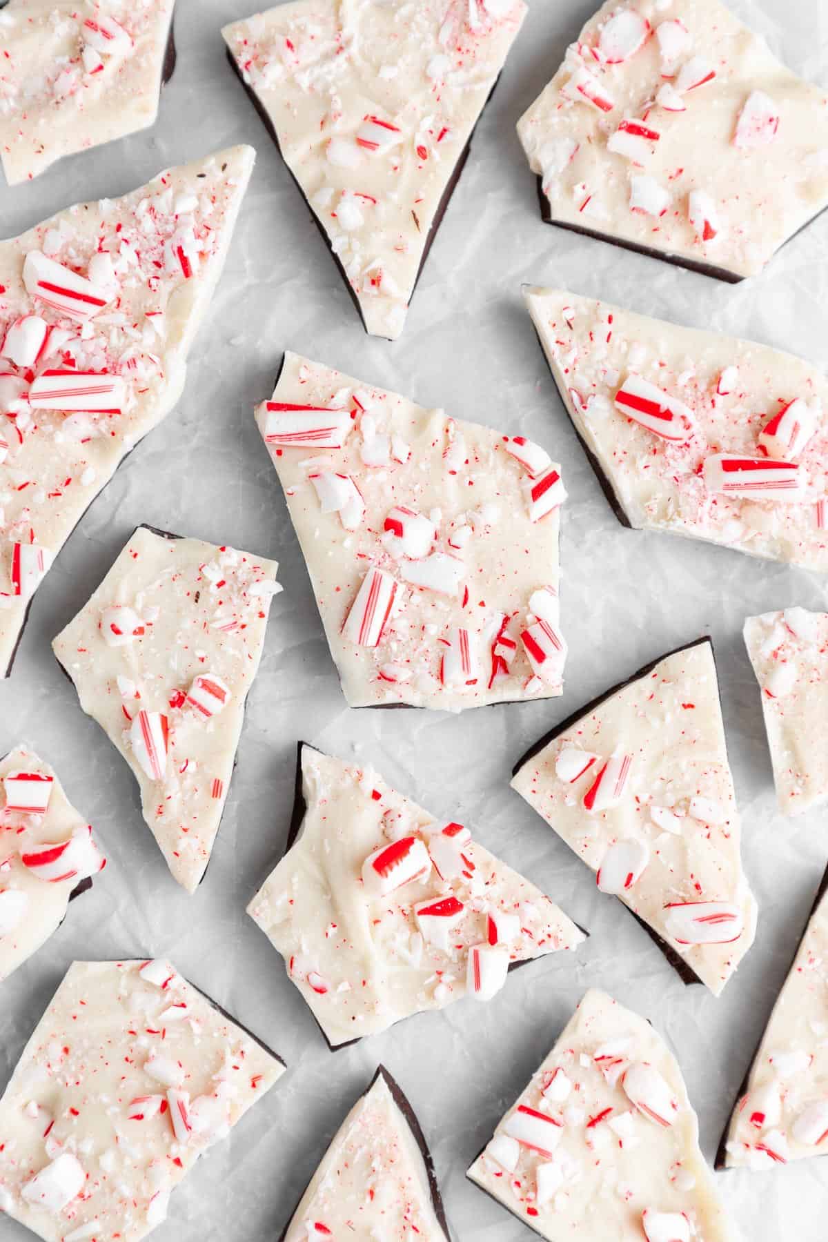 pieces of vegan peppermint bark with candy canes on white parchment paper