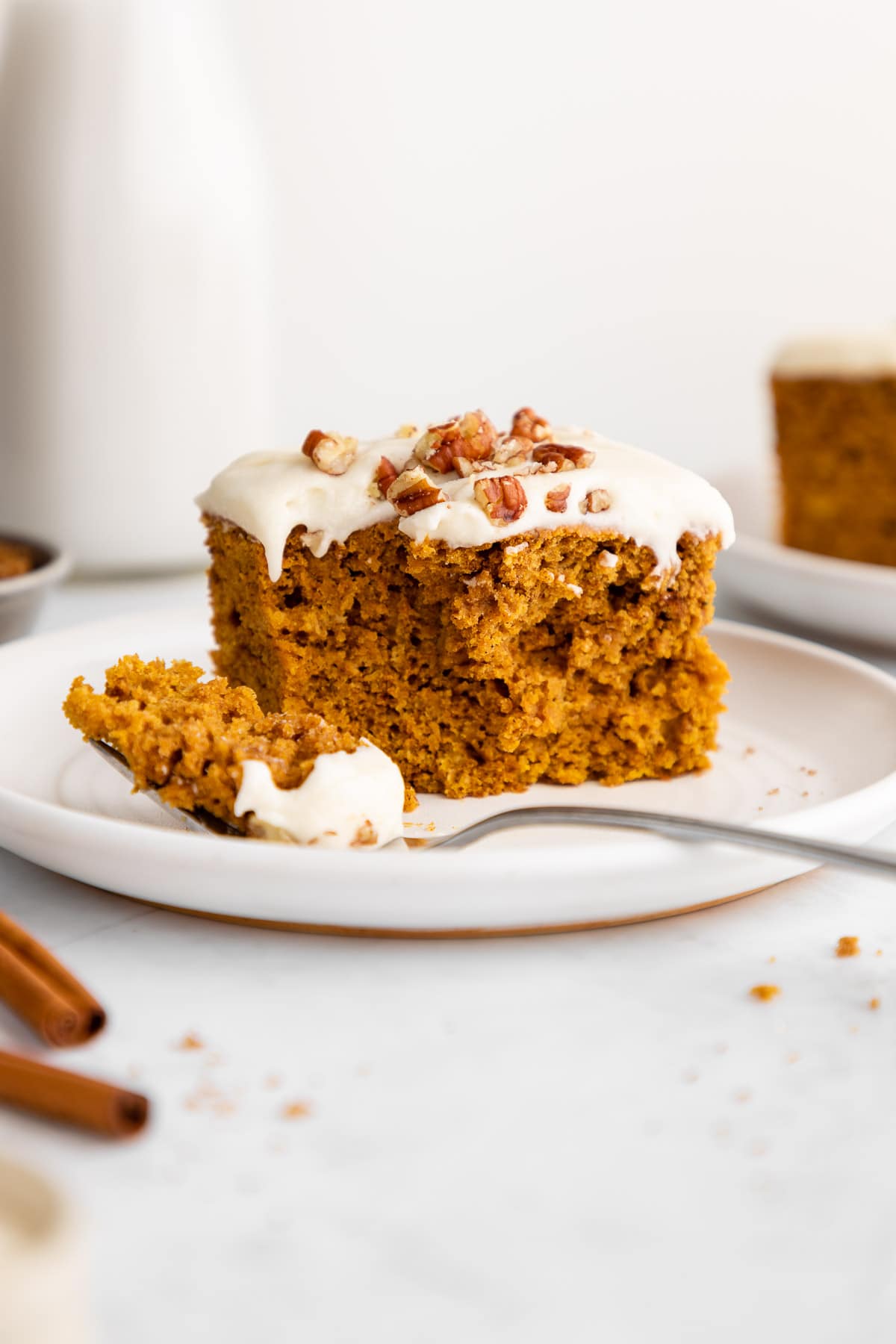 a slice of vegan pumpkin cake with vegan cream cheese frosting on a plate