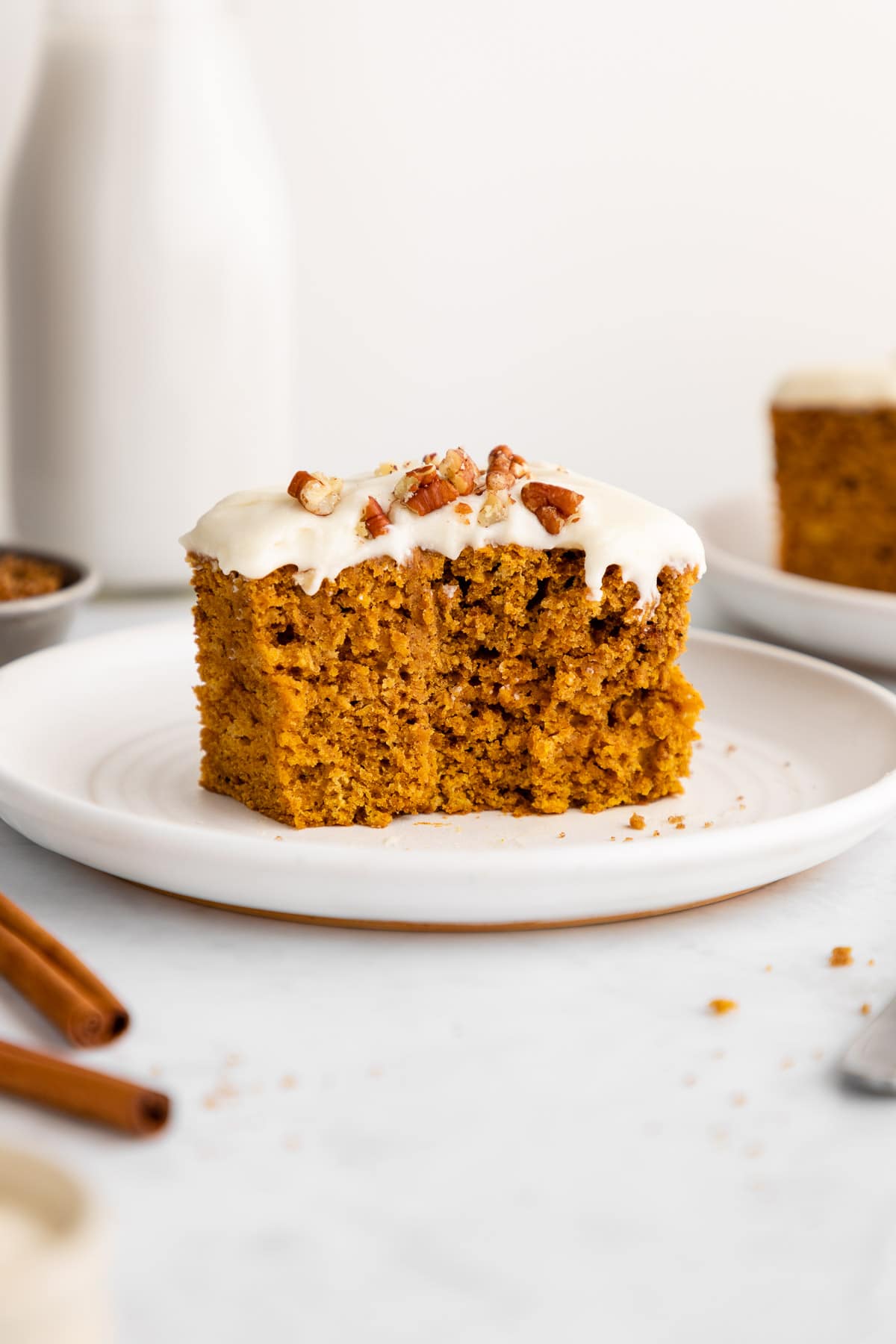 a slice of vegan pumpkin cake with vegan cream cheese frosting on a plate
