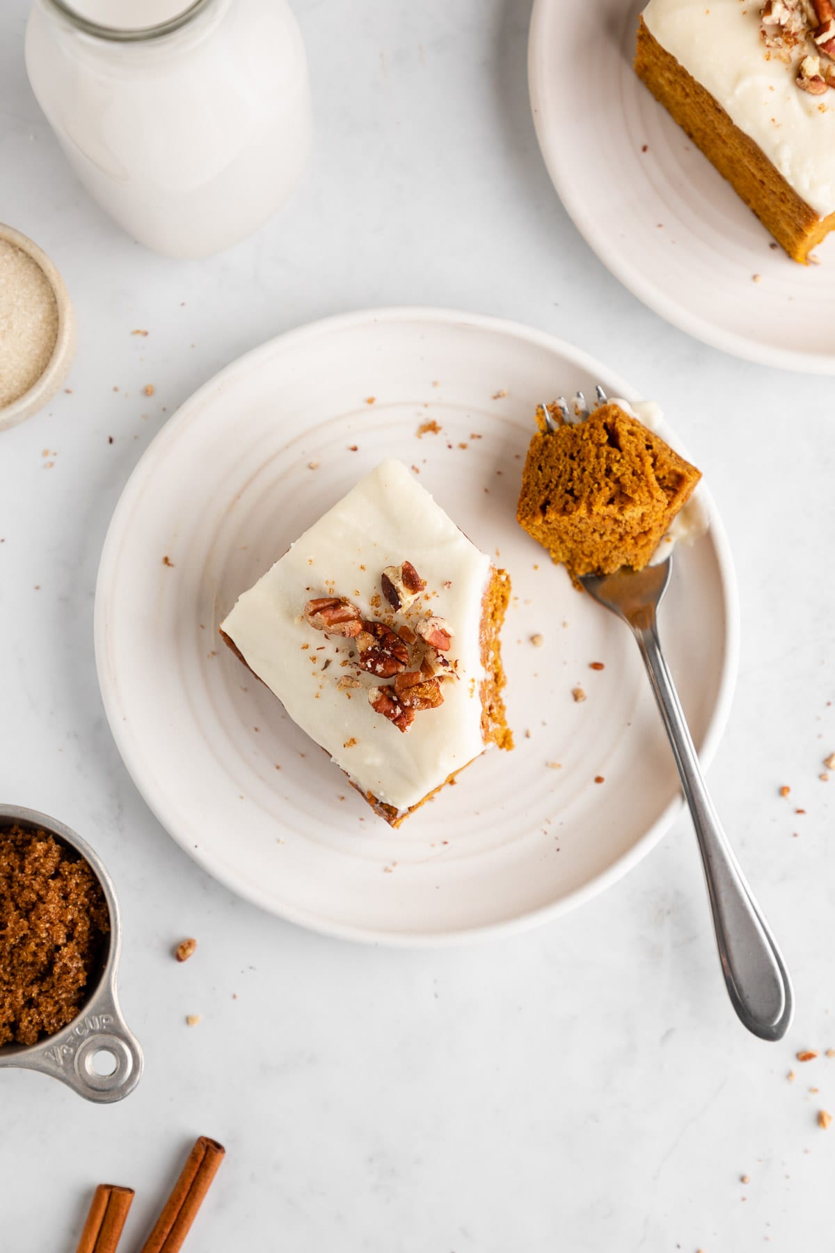 a fork sliced into a piece of vegan pumpkin cake with dairy-free cream cheese frosting