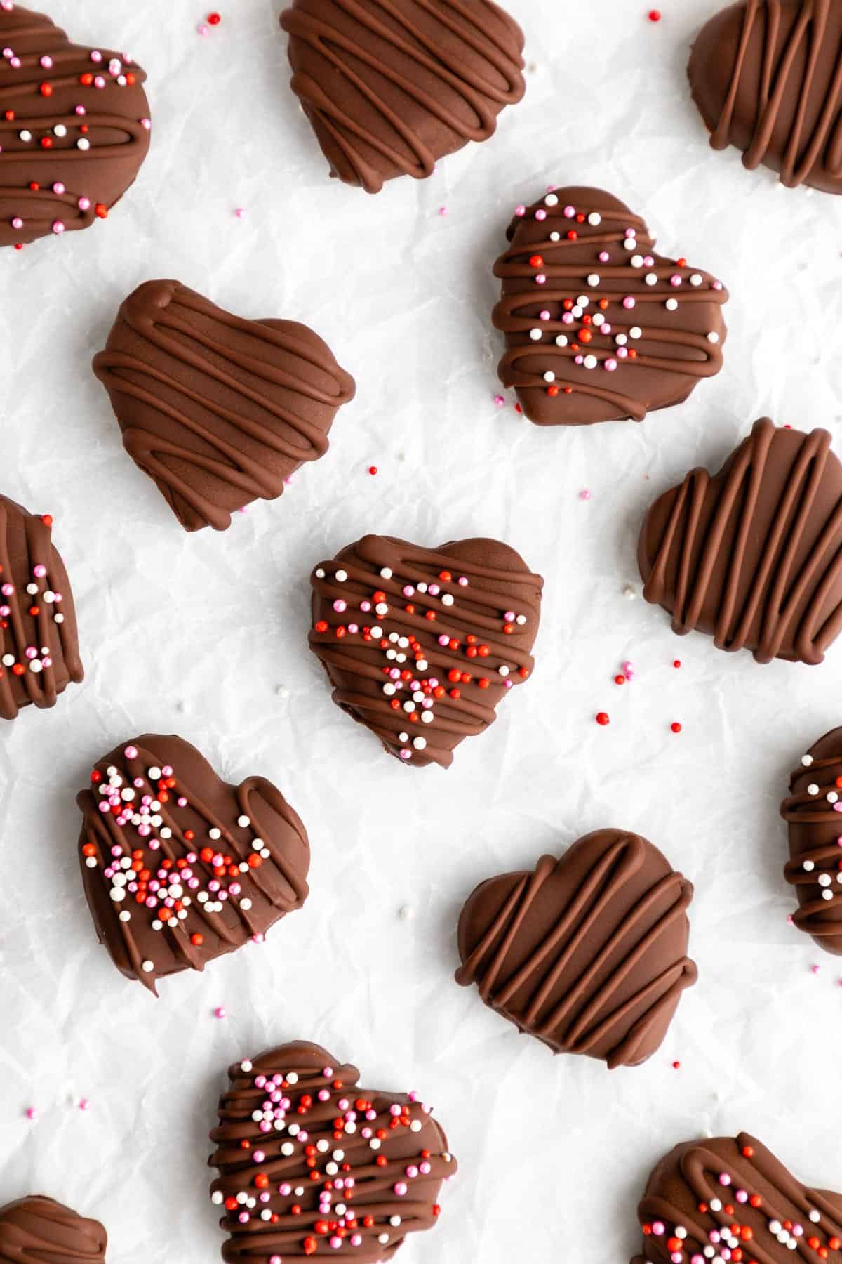 chocolate covered sunbutter hearts with valentines day sprinkles on white parchment paper