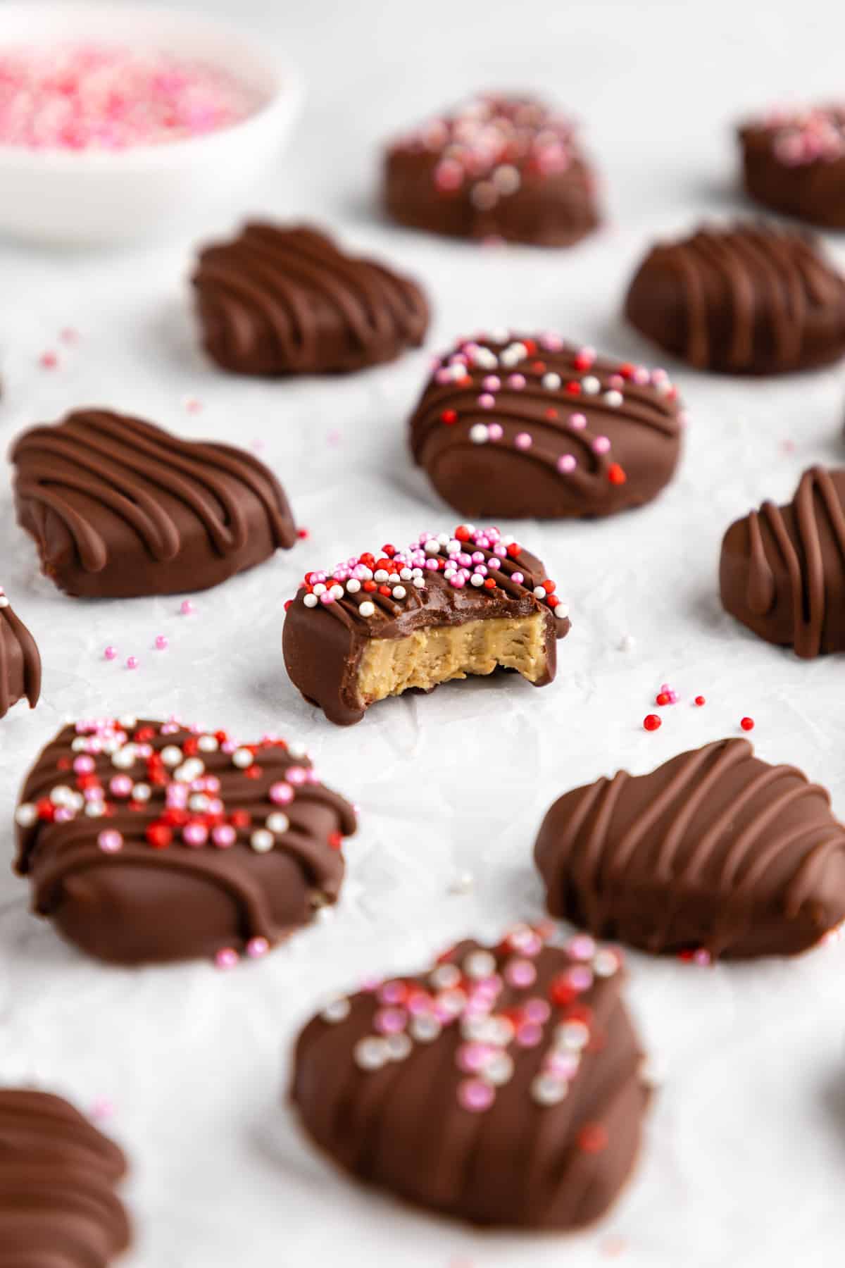 chocolate covered sunbutter hearts with a bite taken out of the center one