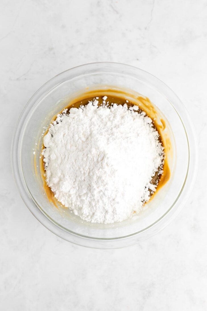 powdered sugar poured over sunflower seed butter in a glass bowl